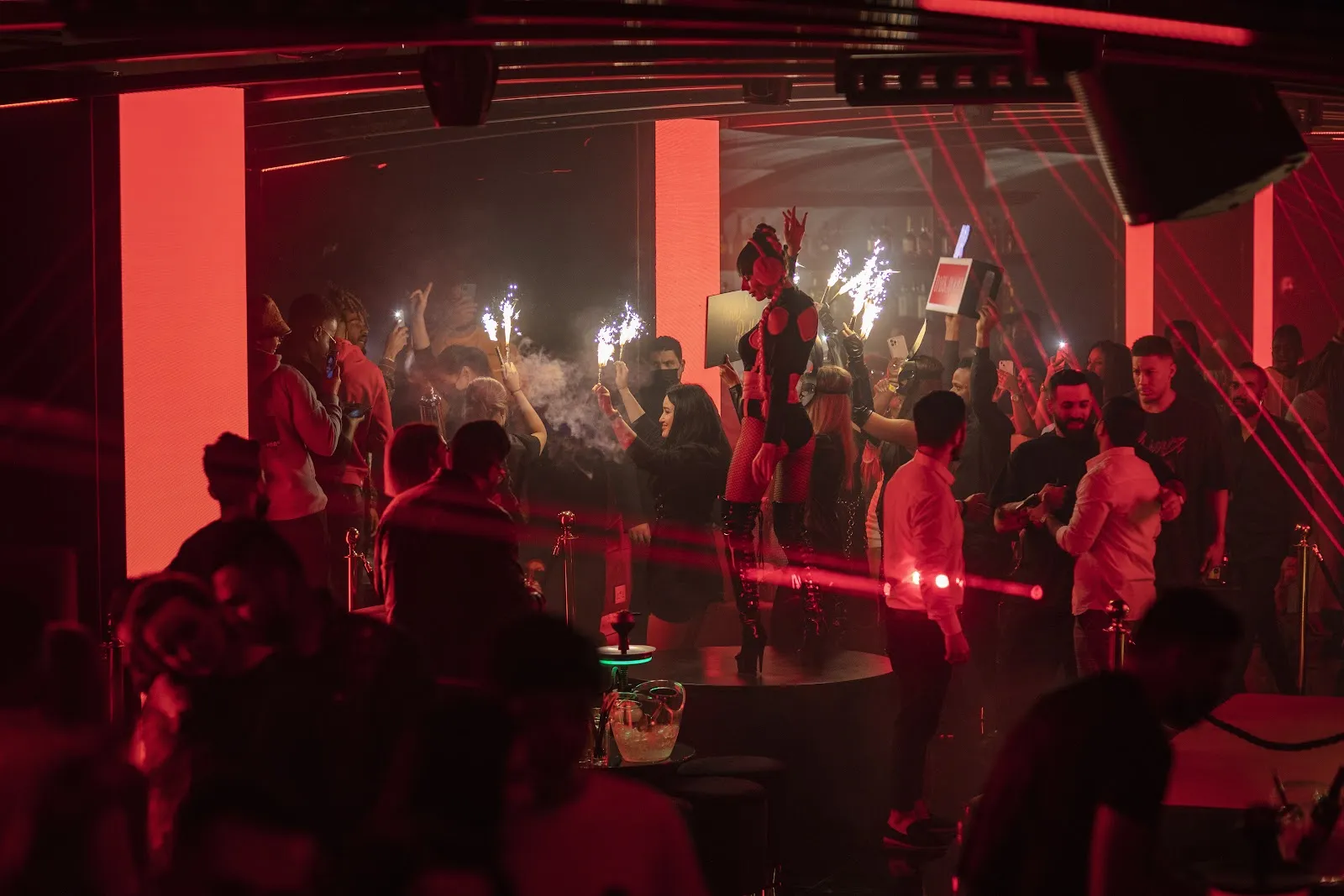 Crowd dancing under red lights on a busy night
